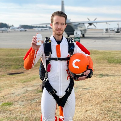 Kasper Kubica photo, in skydiving gear, holding Carpe brand lotion
